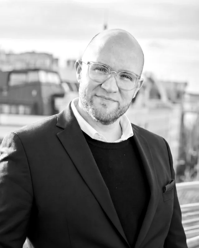 Jan Tewes im dunklen Sakko, im Hintergrund Dächer der Stadt